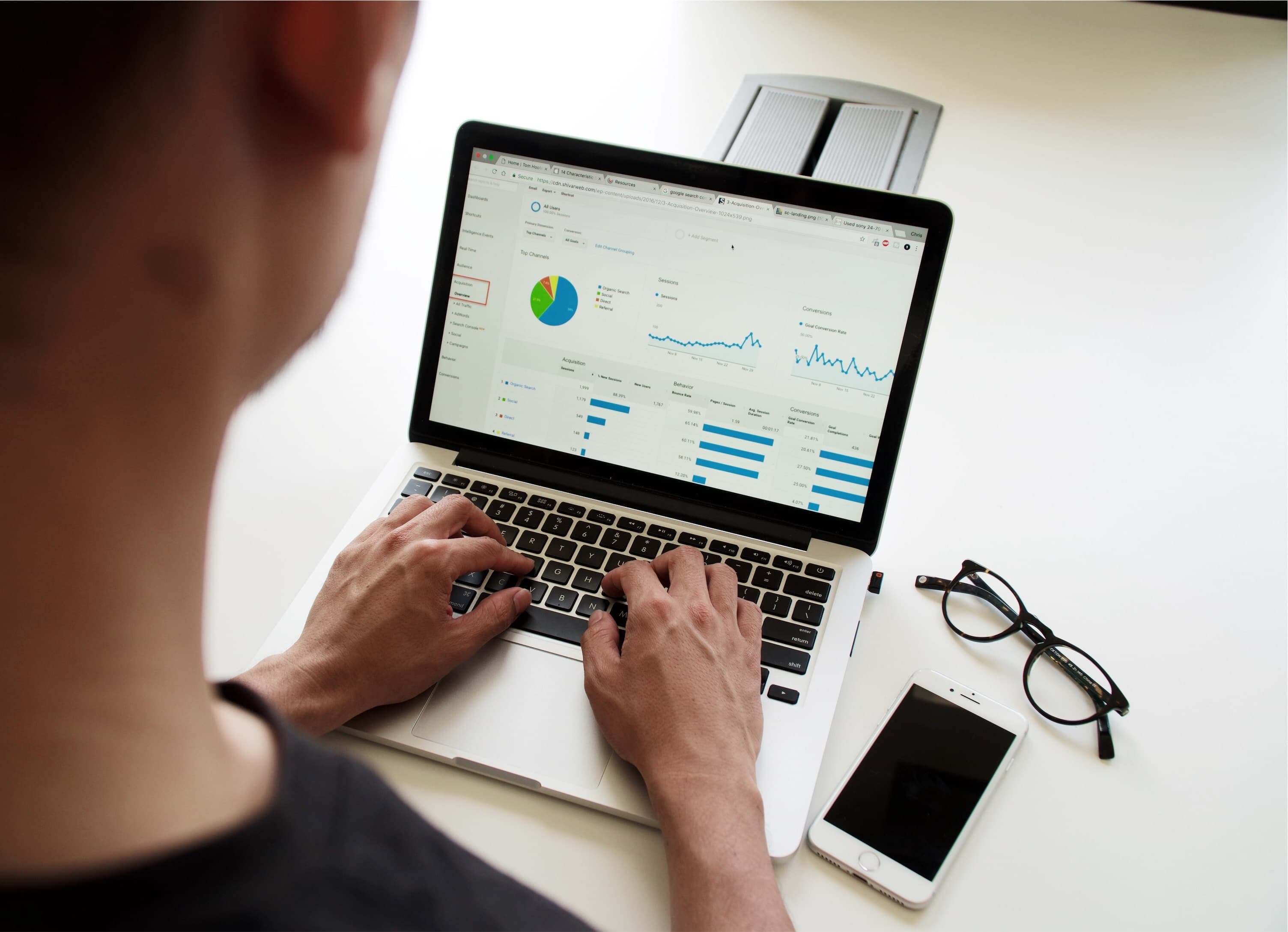 Over-the-shoulder view of someone typing on a laptop looking at charts abd bar graphs